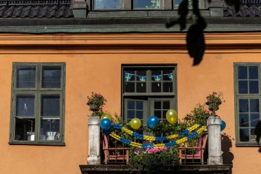Stockholm, İsveç. Şehir merkezinde çiçekli, mavi ve sarı balonlu bir balkon..