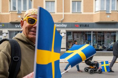 Skelleftea, İsveç 6 Haziran 2023 Sarı gözlüklü bir adam sokaklarda İsveç bayrağı taşıyor.
