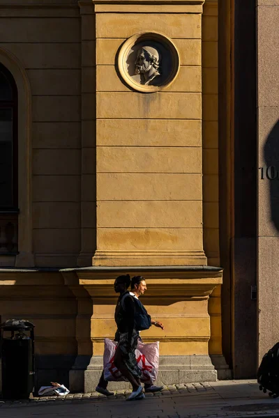 Stockholm, İsveç 14 Haziran 2023. Kasaba merkezindeki Kungstradgarden 'da eski bir turuncu binanın önünden bir kişi geçiyor..