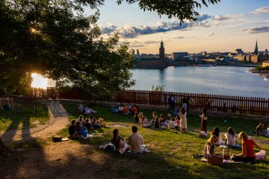 Stockholm, İsveç 24 Haziran 2023 Yaz ortası, Sodermalm 'daki Ivar Lo Parkı' nda gün batımında çimlerin üzerinde oturan insanlar..