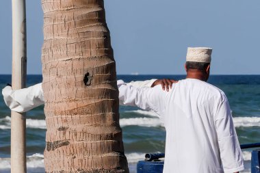 Muscat, Umman 7 Temmuz 2023 plajdaki Omani erkekleri dostluk jesti olarak omuzlarını tutuyorlar..