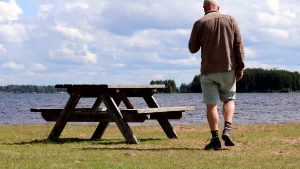 スウェーデンのモーラ夏の日にシルジャン湖のほとりの公園のピクニックテーブルに歩く男 — ストック動画