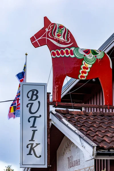 stock image Nusnas, Sweden July 13, 2023 A Dala horse sytands above a sign saying buitk, or store.