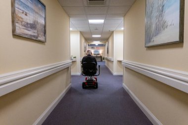 Solomons, Maryland, ABD. Huzurevinde son sınıf öğrencisi. Koridorda elektrikli scooter kullanıyor..