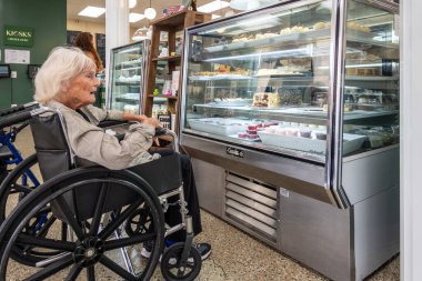 Leonartown, Maryland 4 Ağustos 2023 Tekerlekli sandalyedeki yaşlı bir kadın pastanedeki pasta ve tatlılara hayran..