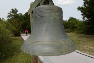 Piney Point, Maryland, ABD 3 Ağustos 2023 Yürüteçli bir adam yürüteçle yürür Piney Point Deniz fenerinde büyük bir çanın yanından geçer.