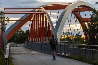 Stockholm, İsveç 'te motosikletli bir adam Vastberga bölgesinde çelik kemerli bir köprüden geçiyor..