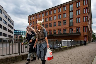 Stockholm, İsveç 12 Ağustos 2023. İki kadın Viking gibi giyinmiş Sodermalm 'da Ringvagen caddesinde yürüyor..