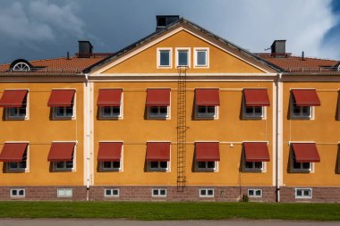 Mora, İsveç. Mora Sosyal Hizmetler binasının simetrik portakal rengi cephesi. Yaz güneşinde kırmızı güneşlik güneşlikler..