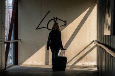 Stockholm, İsveç 21 Ağustos 2023 Bir kadın yolcu yolcu feribotuna binmek için koridorda tekerlekli bavulla yürüyor..