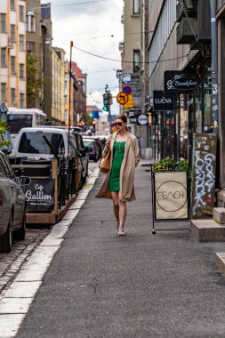 Helsinki, Finlandiya 22 Ağustos 2023 Tasarım Bölgesi 'nde elinde sigarayla genç ve şık bir kadın sokakta yürüyor..