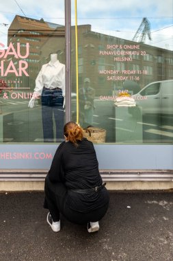 Helsinki, Finlandiya 22 Ağustos 2023 Bir giyim mağazasındaki kadın mağaza görevlisi açık pencereyi ölçer.
