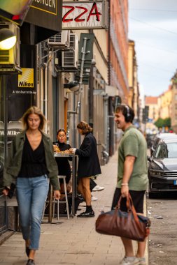 Stockholm, İsveç 5 Eylül 2023 Sodermalm bölgesinde iki genç kadın bir erkek ve bir kadın olarak pizza yiyorlar..