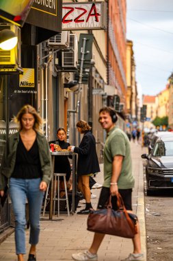 Stockholm, İsveç 5 Eylül 2023 Sodermalm bölgesinde iki genç kadın bir erkek ve bir kadın olarak pizza yiyorlar..