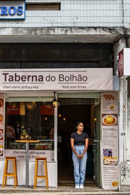 Porto, Portekiz 'de bir kadın garson Portekiz yemekleri üzerine uzmanlaşmış küçük bir restoranın önünde duruyor..