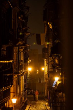 Porto, Portekiz 20 Eylül 2023 Ribeira bölgesindeki Rua de Tras 'da karanlık ve ıslak bir gecede yürüyen yayalar..