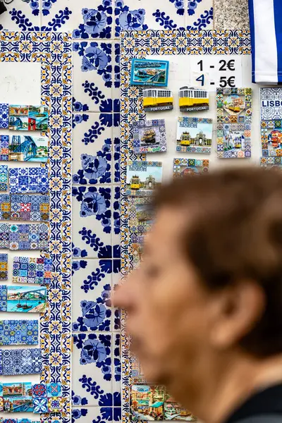 ポルトガル ポルトガル 2023年9月20日 ノイポップンで花束を付けた女性が 磁石やタイルなどの陶磁器のお土産の壁を通り過ぎる — ストック写真