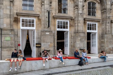 Porto, Portekiz 20 Eylül 2023. Ribeira bölgesindeki kırmızı yastıklarda oturan insanlar, bir kafenin önünde, S. Domingo Caddesi 'nde oturuyorlar..