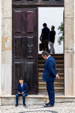 Aveiro, Portekiz 20 Eylül 2023 Igreja Da Misericordia De Aveiro 'da ya da yetişkin bir adamın izlediği Merhamet Kilisesi' nde genç bir çocuk cep telefonuyla oynuyor..