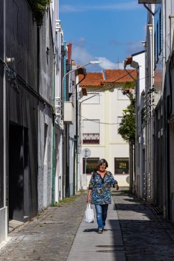 Aveiro, Portekiz 20 Eylül 2023 Bir kadın alışveriş çantasıyla dar bir sokakta yürür.