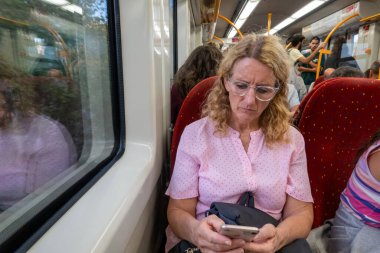 Porto, Portekiz 20 Eylül 2023. Bir kadın dolu bir banliyö trenine binerken telefonunu kontrol ediyor..