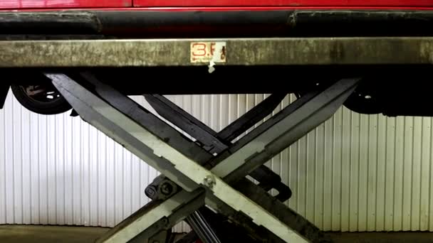 ストックホルム スウェーデン ガレージの油圧リフトで赤い車を持ち上げます — ストック動画