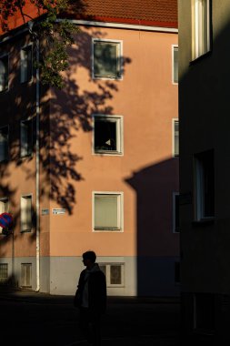 Stockholm, İsveç 4 Ekim 2023 Öğleden sonra güneş ışığında Aspudden bölgesinde güçlü gölgelerle yürüyen insanlar.