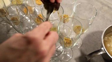 Bir kadın, doğum günü partisinde kokteyl için şampanya bardaklarına tutku meyvesi karıştırır. 