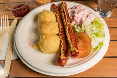 Patates püresi ve karides salatasıyla servis edilen iki sosisli..