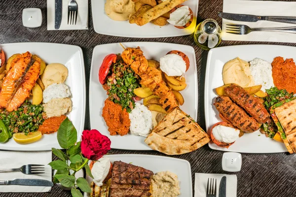 A display at a restaurant of Middle Eastern foods with beef, hummus, babaganoush,