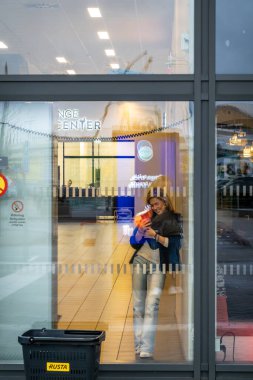 Stockholm, İsveç 9 Kasım 2023 Arninge İstasyonu alışveriş merkezinin vitrininde telefonuyla genç bir kadın duruyor..