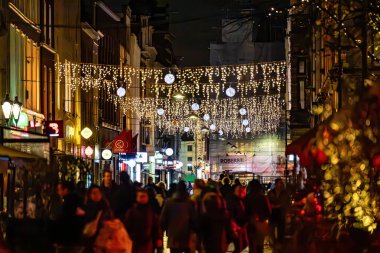 Lahey, Hollanda 10 Kasım 2023 Noel süsleri ile merkez iş bölgesinde gece bir sokakta yürüyen insanlar.