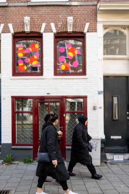 Rotterdam, Hollanda, 11 Kasım 2023 Oude Noorden bölgesinde renkli bir ev ve pencerenin önünden geçen bir grup kadın..