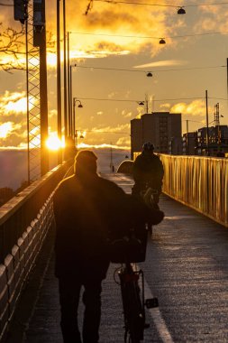 Stockholm, İsveç 22 Kasım 2023 Lljeholmen Köprüsü bisikletçileri kış ortasında gün batımında.