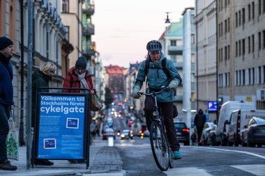 Stockholm, İsveç 21 Kasım 2023 Odenplan bölgesindeki Surbrunnsgatan 'da yeni açılan bisiklet yolunda bisiklet sürücüleri ve İsveççe 