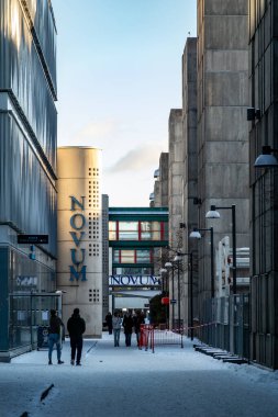 Stockholm, İsveç 27 Kasım 2023 Huddinge banliyösündeki arabasız bir sokakta yürüyen insanlar Novum işareti altında Huddinge Hastanesi 'ne yakın..