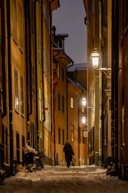 Stockholm, İsveç Eski Şehir 'in dar, karlı sokaklarında yürüyen bir kadın ya da kışın Gamla Stan.