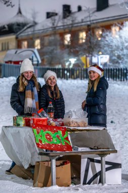 Stockholm, İsveç 7 Aralık 2023. Genç kızlar kar yağışlı bir akşamda Kronobergspark 'ta küçük bir şekerleme ve içecek büfesi..
