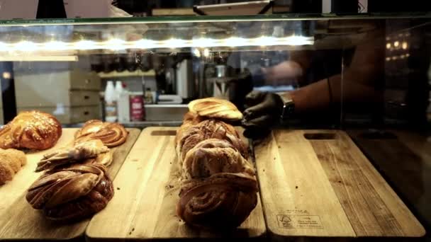 스톡홀름 스웨덴 카페의 서버는 크로이센트와 달콤한 빵으로 디스플레이 케이스를 채웁니다 — 비디오