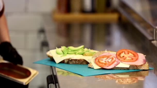 ストックホルム スウェーデン カフェの男性サーバーは ステンレスキッチンカウンターでサンドイッチを作ります — ストック動画