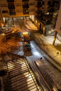 Stockholm, İsveç 13 Aralık 2023. Sabahın erken saatlerinde kar altında kooperatif bir apartmanın bahçesinde bir çöp kamyonu..