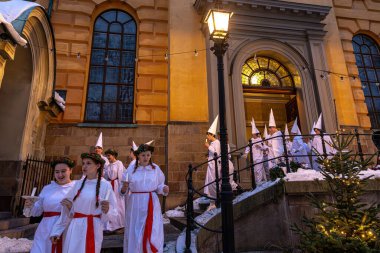 Stockholm, İsveç 13 Aralık 2023 geleneksel Lucia korosu kostümlü kızlar ve oğlanlar Ostermalm 'daki Hedviq Eleanora Kilisesi' nden çıkarken sabah erken saatlerde Lucia konserine imza attılar..