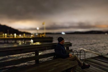 Stockholm, İsveç 'te Ekero banliyösündeki Malaren Gölü' ndeki küçük bir rıhtımda bir adam oturuyor..