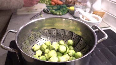 Erkek bir aşçı, bir mesken mutfağında buharlaşmak için Brüksel lahanası soyar.. 