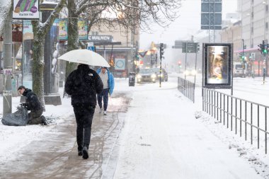 Stockholm, İsveç, 22 Aralık 2023 Bir adam Sodermalm 'daki Medborgarplatsen' de yağmurda şemsiyeyle yürüyor.