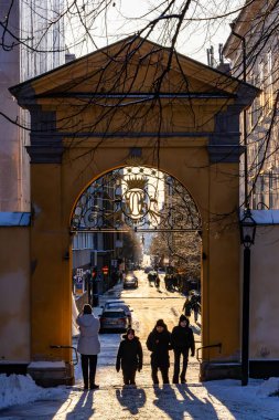 Stockholm, İsveç, 24 Aralık 2023 güneşli bir günde Katrain Kilisesi mezarlığında yürüyen yayalar ve Sodermannagatan 'a giden kemerli bir yol..