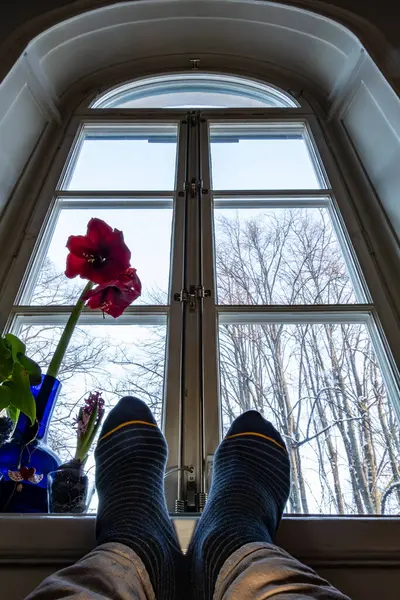 Stockholm, Sweden, A man\'s feet rest in the windowsill of an aprtment building.