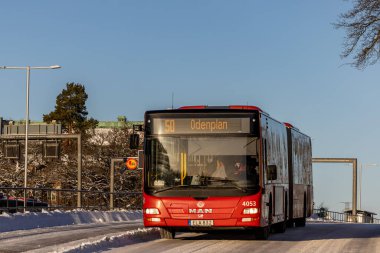 Stockholm, İsveç 27 Aralık 2023. Buzlu bir yolda kırmızı bir belediye otobüsü..