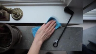 Bir kadın bir apartmanın pencerelerini silmek için bez kullanıyor..