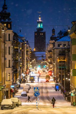 Stockholm, İsveç 2 Ocak 2024. Hantverkargatan Caddesi 'nde ve Kungsholmen İlçesi' nde belediye binasında gece vakti bir kadın elektrikli scooter kullanıyor..